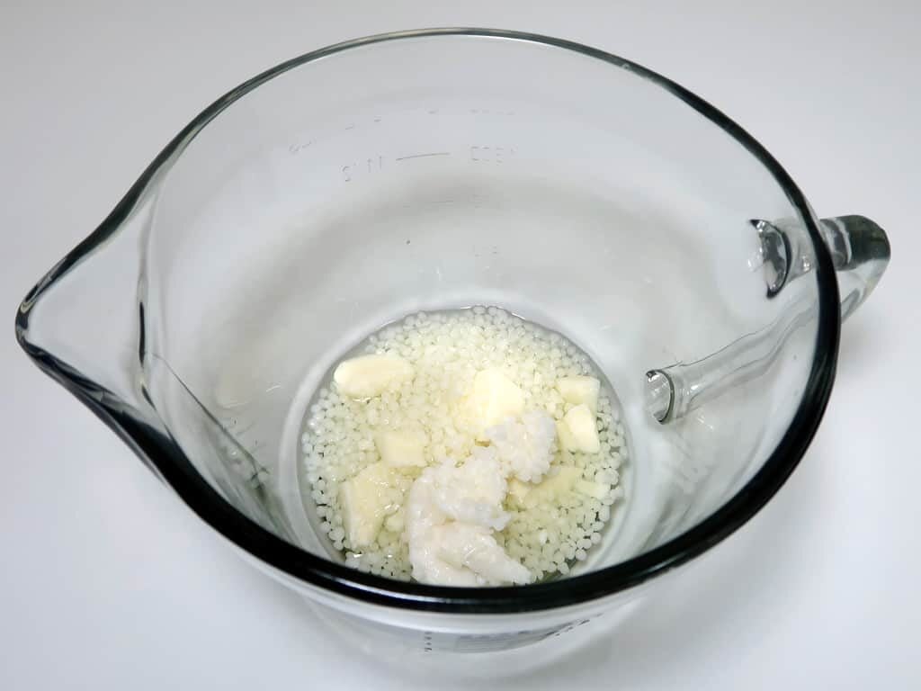 Weigh out your cocoa butter, shea butter, beeswax, and coconut oil into a medium glass or metal bowl