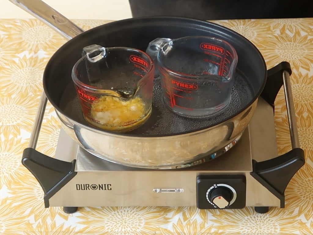 Sit both the water and oil containers into the simmering water