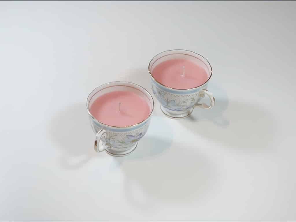 Two tea cup candles sitting on a white table