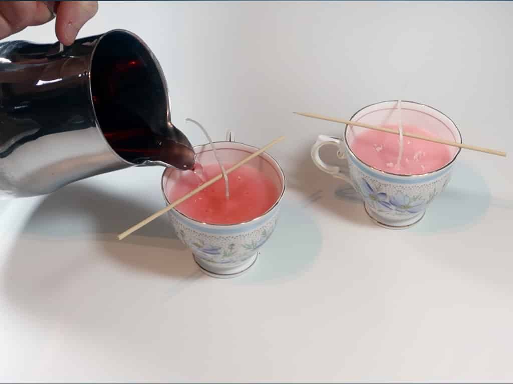 Melted wax being poured into holes poked into the tea cup candles