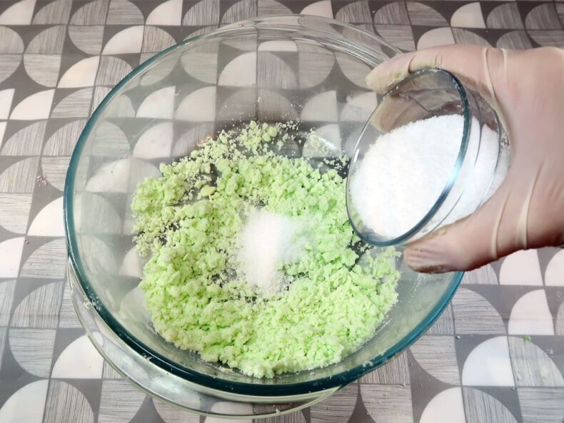 A woman adds citric acid to her bath bomb mixture