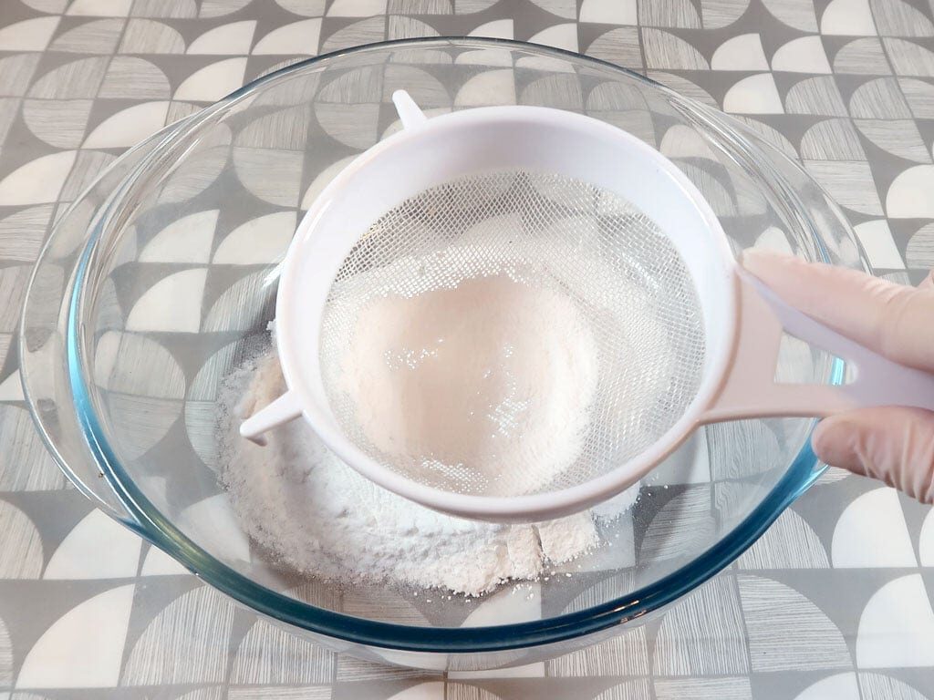 A woman sifts baking soda so there are no lumps