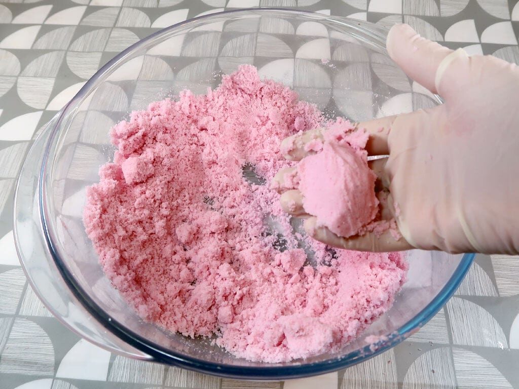 A woman tests the moisture content of her bath bomb mixture