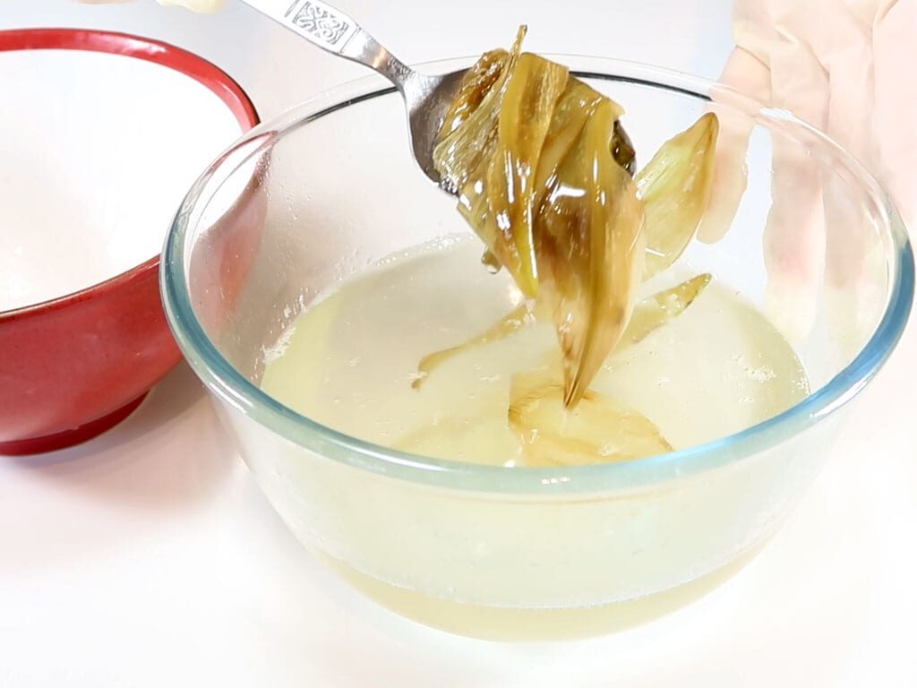 Petals being removed from liquid coconut oil into a bowl