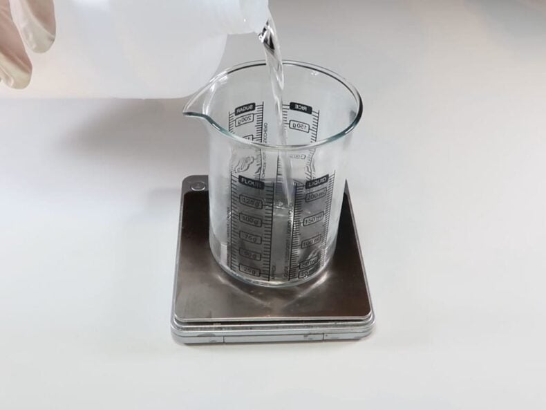 perfumers alcohol being added to a glass beaker sitting on digital scales