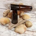 Two oil based roll on perfumes with some drift wood, shells and stones; Island Haze