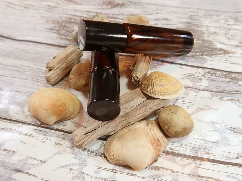 Two oil based roll on perfumes with some drift wood, shells and stones; Island Haze