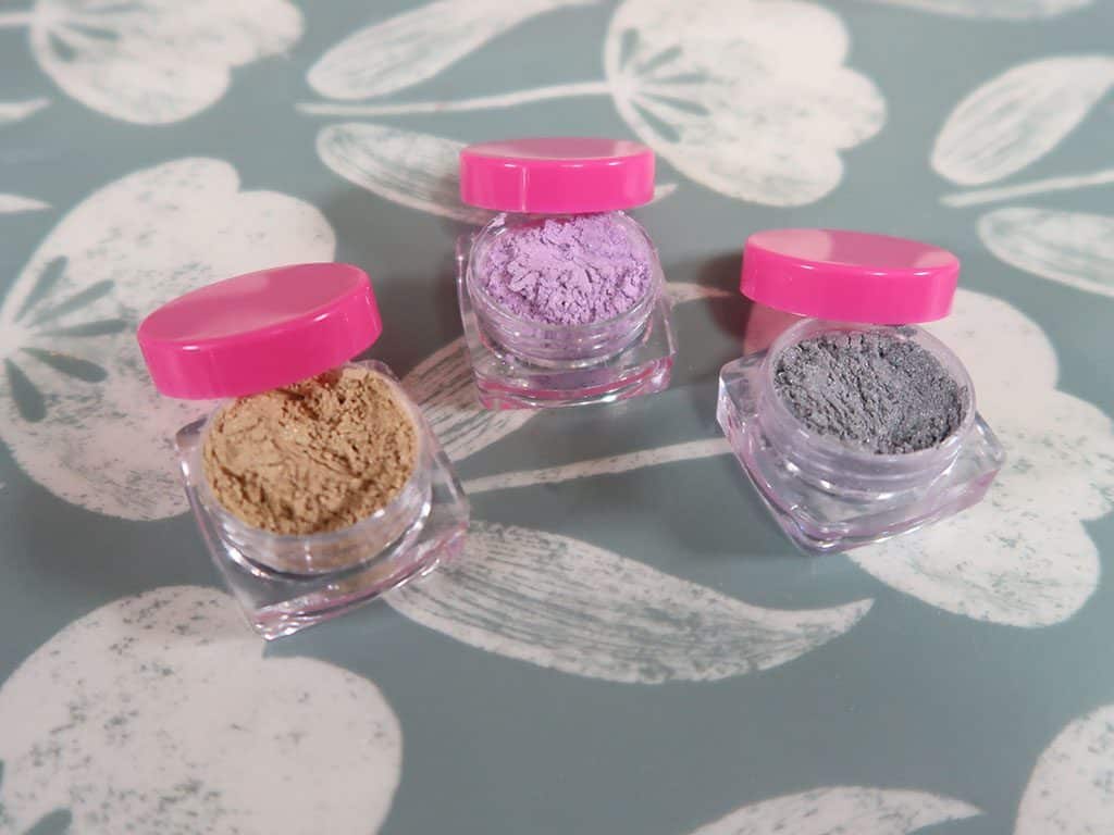 Three eye shadows sit together, all of different colors