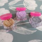 Three eye shadows sit together, all of different colors