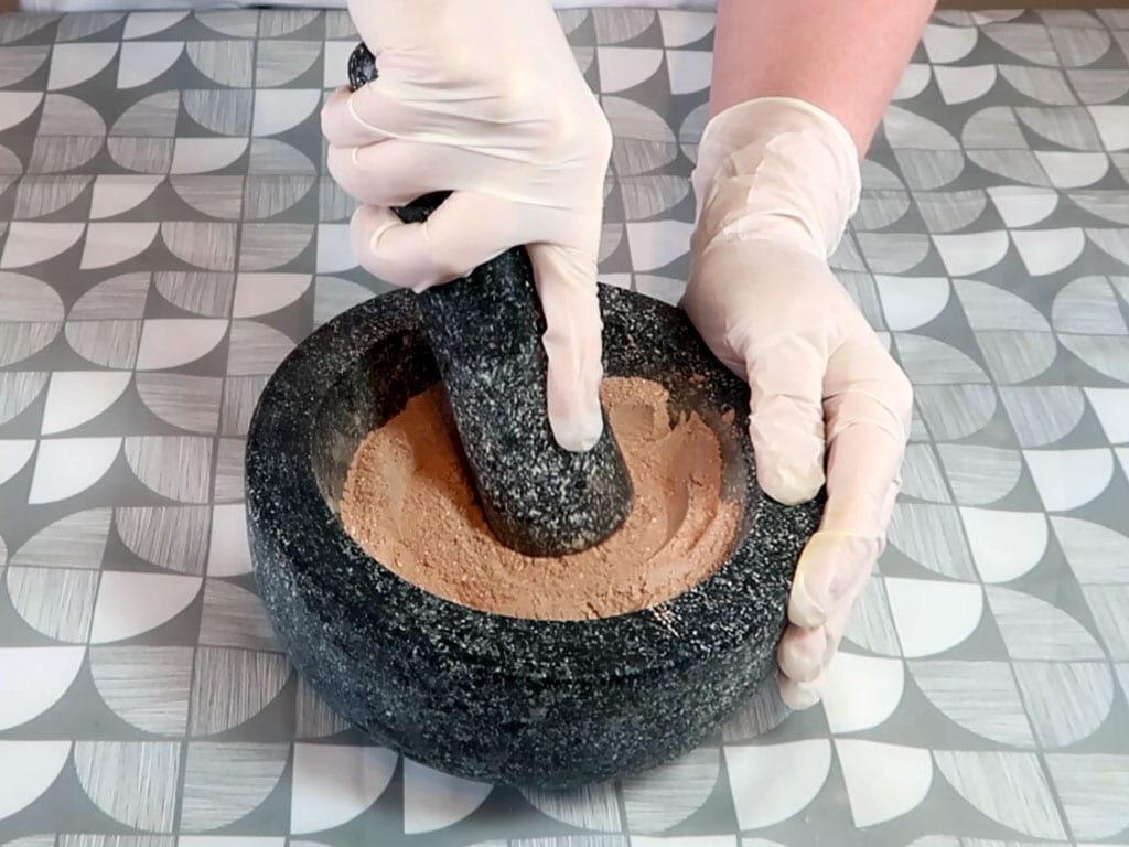 Powdered ingredients being ground in a mortar and pestle