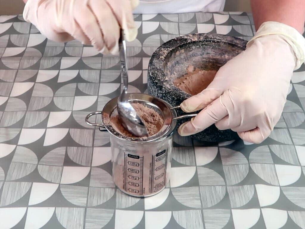 Powder being sieved into a beaker