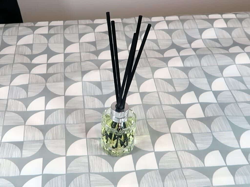 A reed diffuser sits on a table