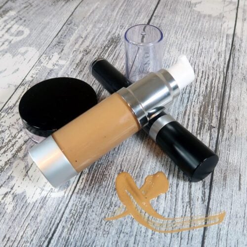Liquid foundation sitting with a blush sifter and mascara tube