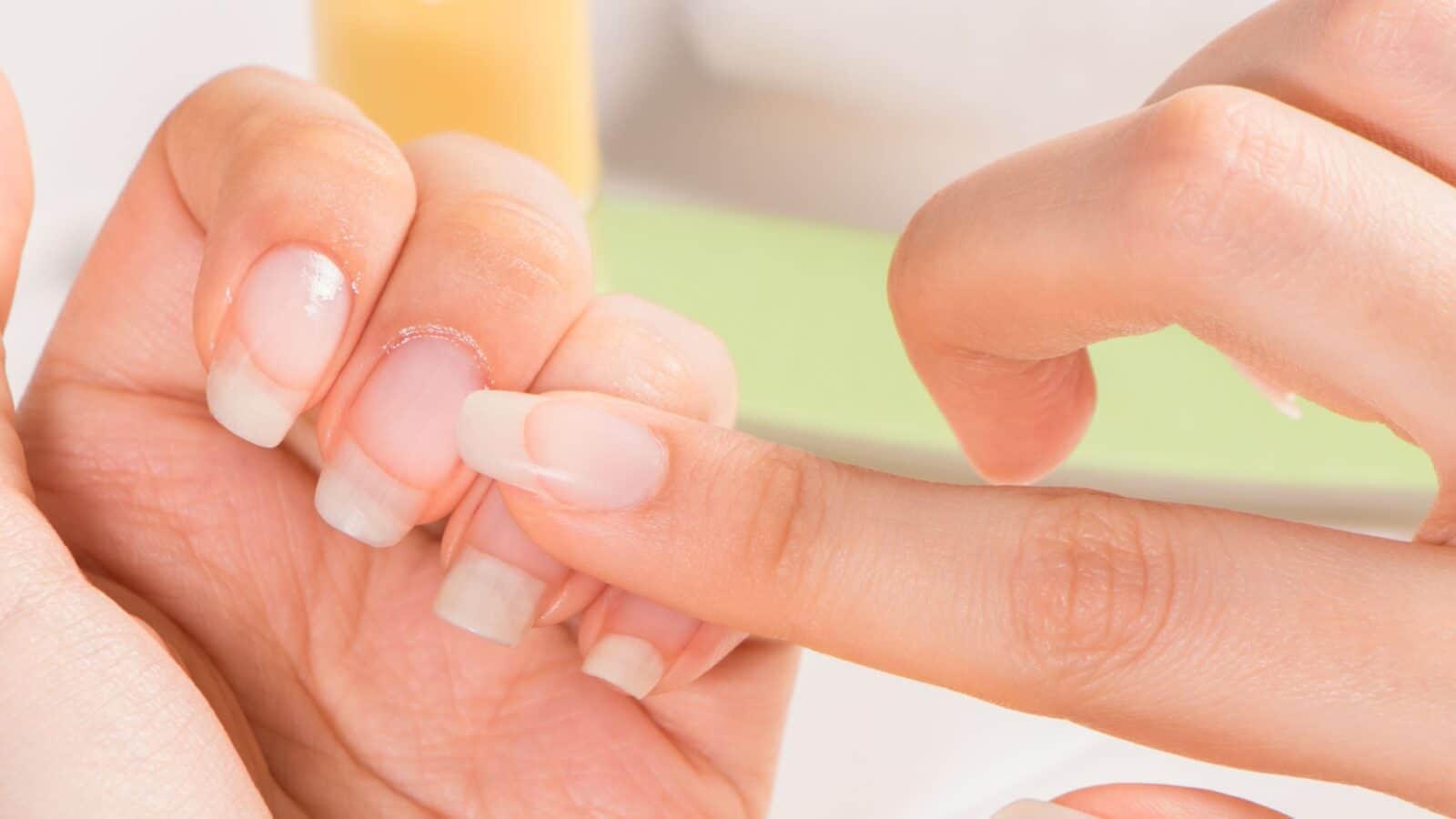 close up of women applying oil to finger nails cuticles