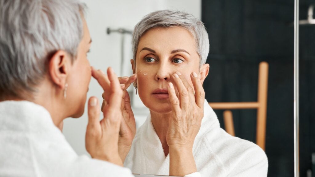 Mature woman applying moisturizer