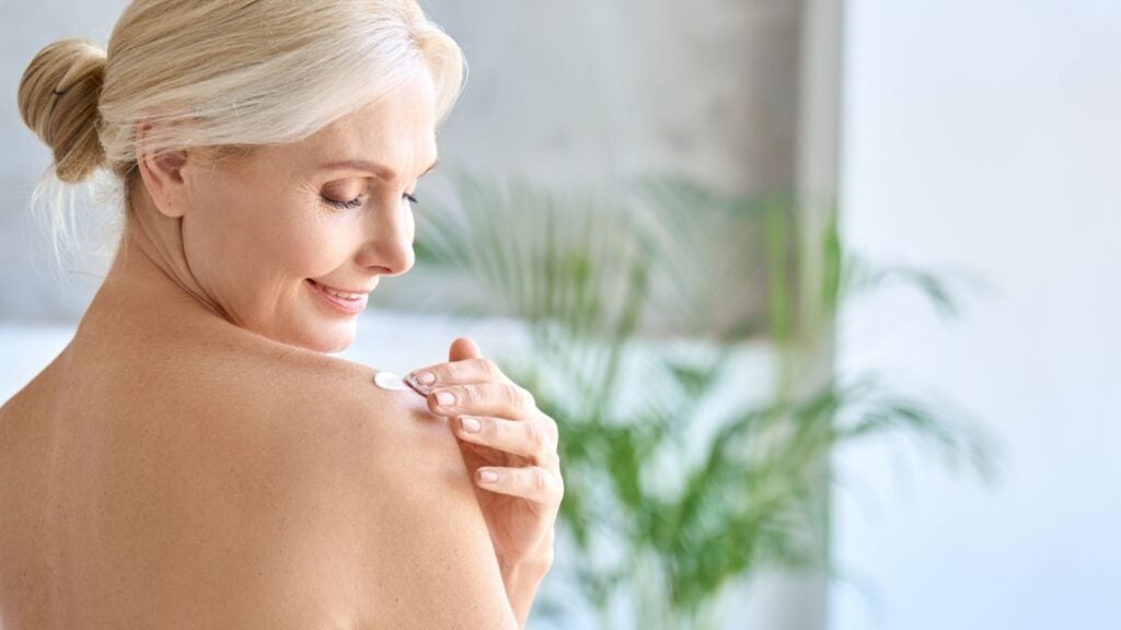 mature women applying body lotion butter