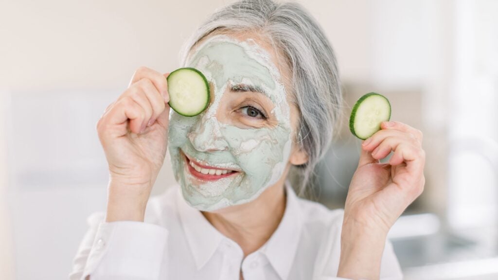 senior woman, holding cucumber piece over one eye and smiling senior woman, holding cucumber piece over one eye and smiling