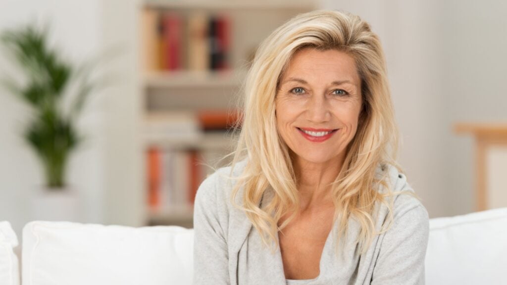 Attractive stylish mature blond woman sitting on a sofa
