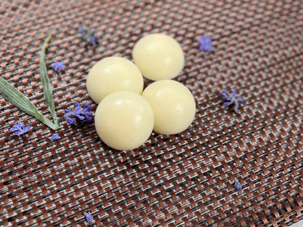 Lavender and goats milk conditioning bars sit next to purple flowers
