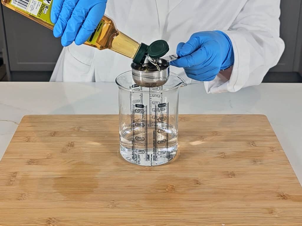 Cider vinegar is measured into the glass beaker with the water