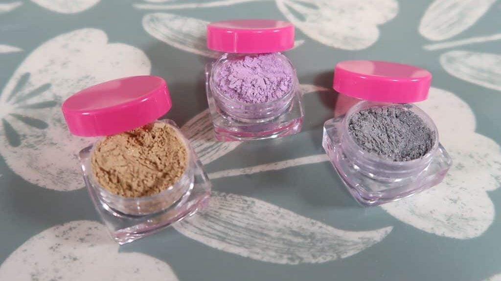 Three eye shadows sit together, all of different colors