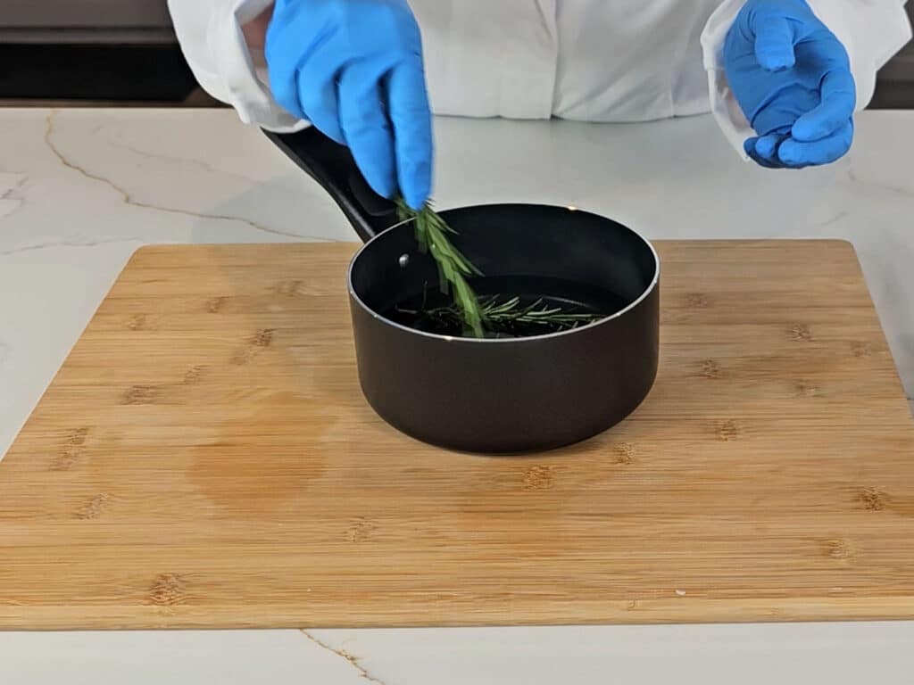 Rosemary sprigs are added to the pan