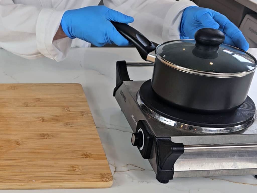 The pan now has a lid on and is placed on a hotplate to simmer on a medium heat