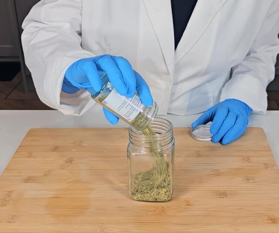 Dried rosemary is poured into a mason jar