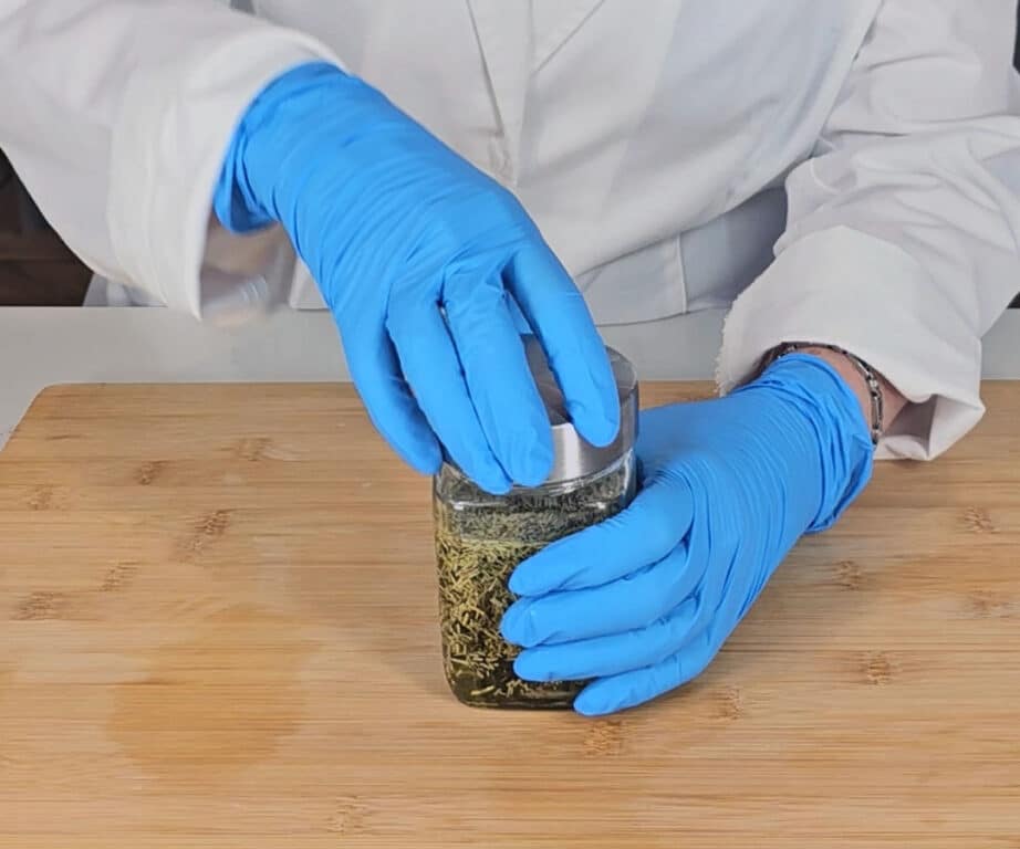 The lid is applied to the jar of rosemary and carrier oil