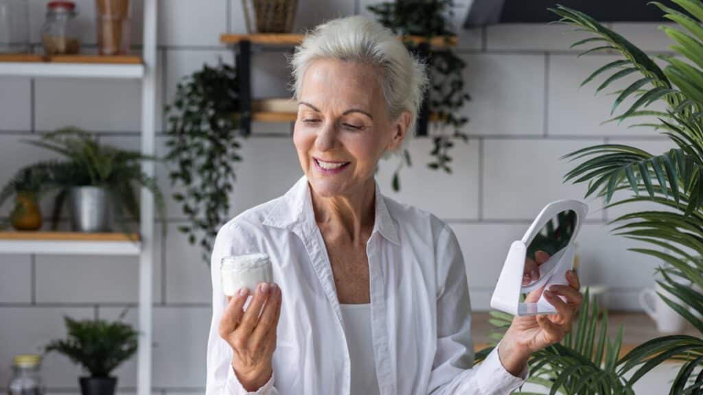mature senior woman holding pot of face cream lotion