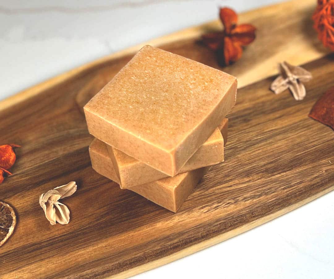 Three bars of natural homemade turmeric soap sit on a wooden board Three bars of natural homemade turmeric soap sit on a wooden board