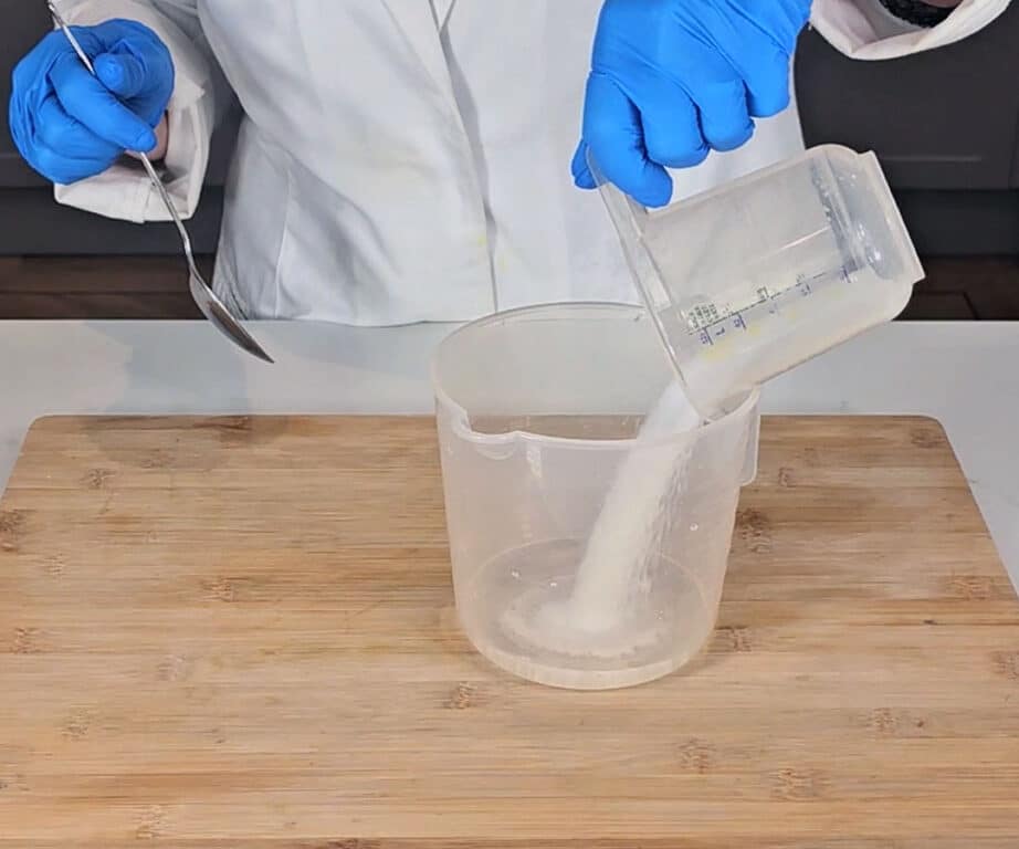 Sodium hydroxide crystals are poured into a pitcher of distilled water