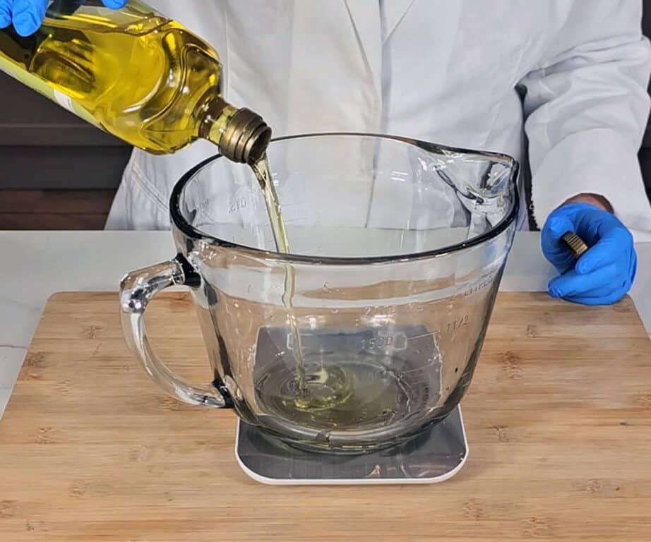 Olive oil is poured into a large glass mixing bowl