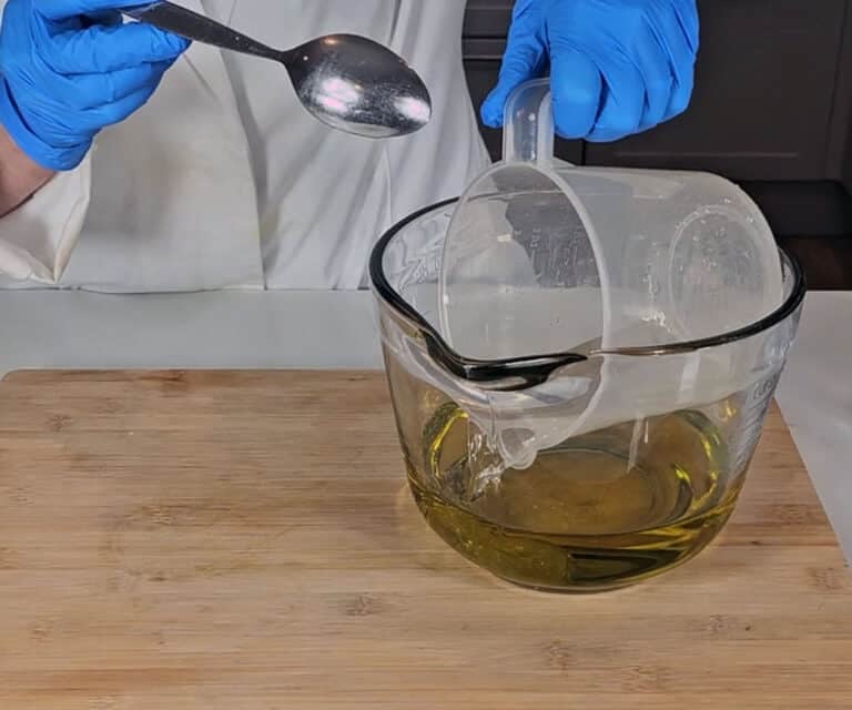 The lye solution is poured into the mixing bowl of olive oil