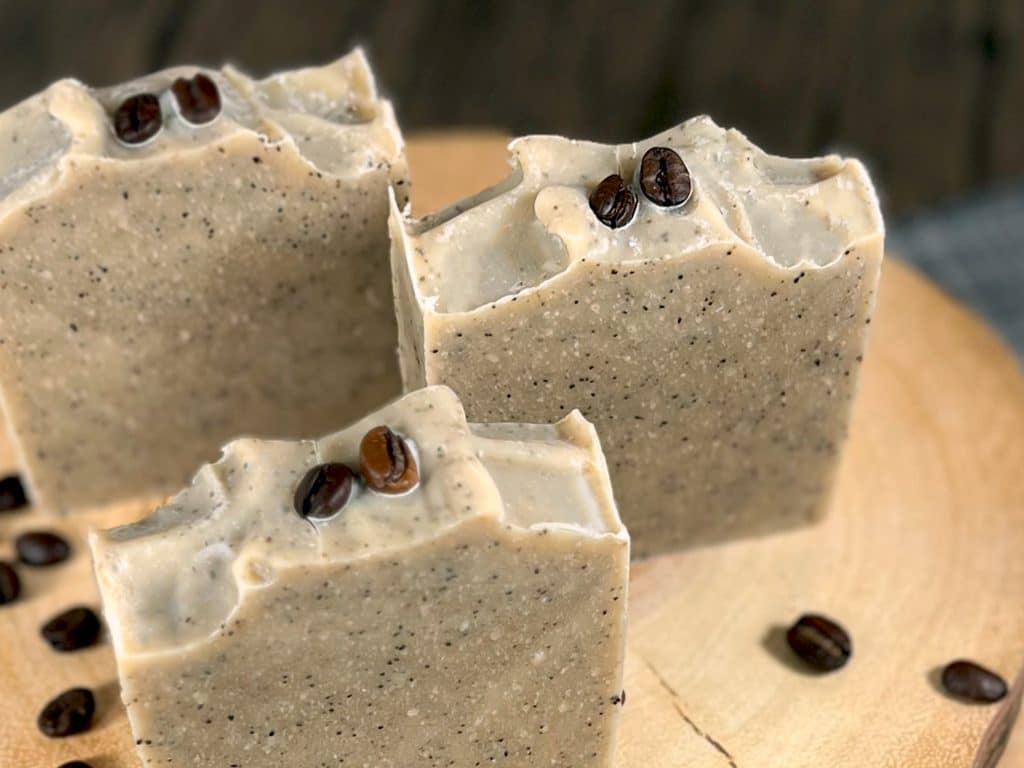 Three bars of DIY coffee soap, with coffee beans surrounding it Three bars of DIY coffee soap, with coffee beans surrounding it