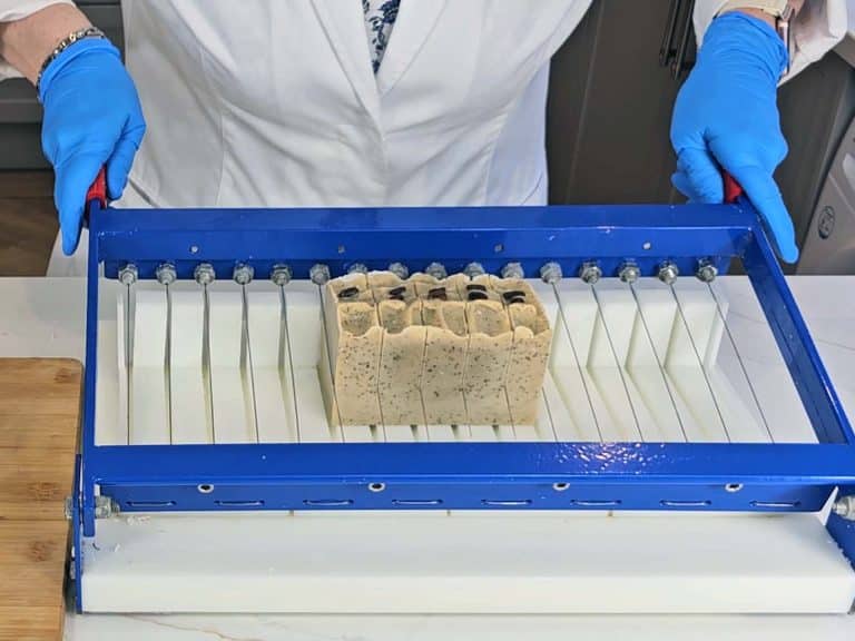 The loaf of soap is cut into bars using a soap cutter