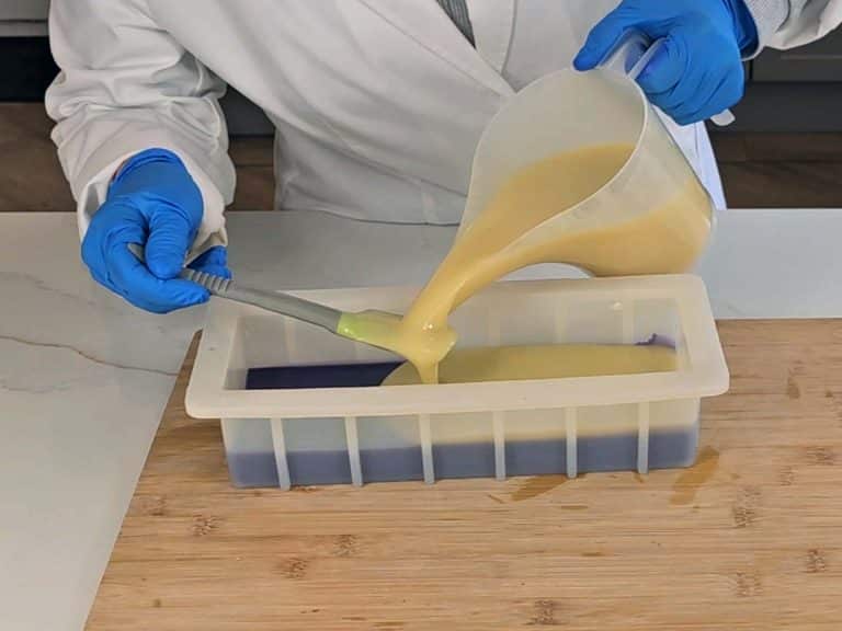 The undyed soap batter is layered ontop of the surple soap batter in the mold