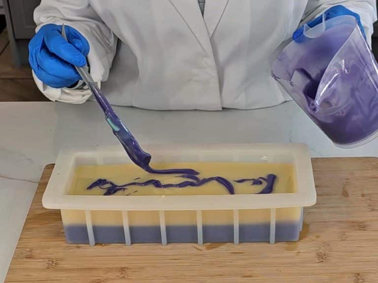 Leftover purple soap batter is spooned onto the surface of the undyed soap batter