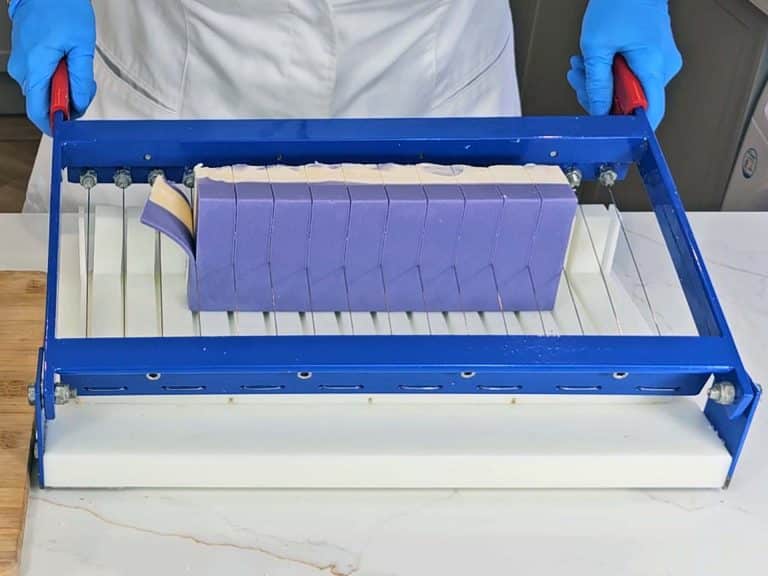 The finished soap is cut into bars using a manual soap cutter