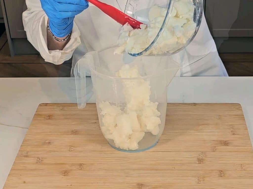 Coconut oil is measured into a plastic pitcher