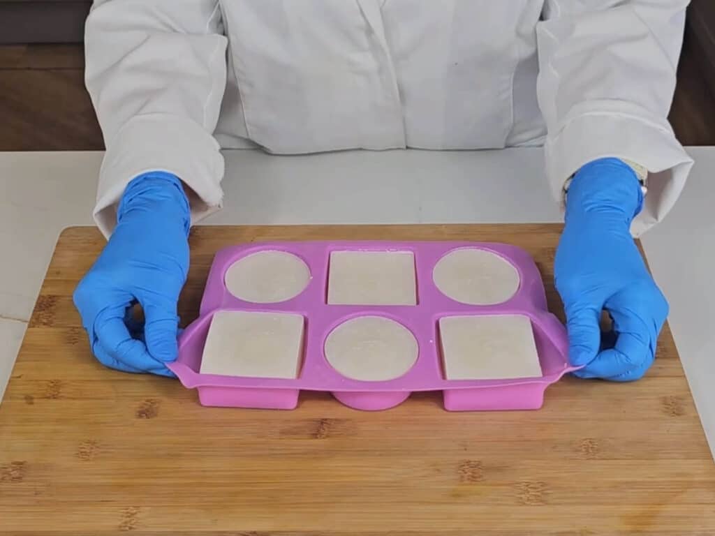 The silicon mold is pulled on either side to help release the hardened soaps from their molds.