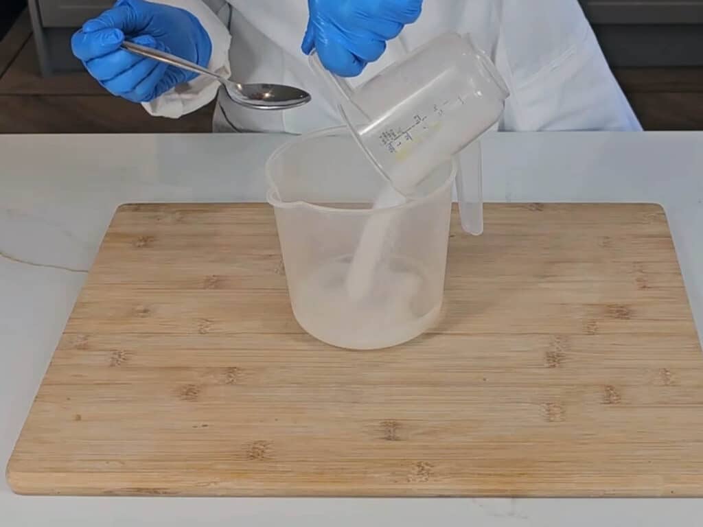 Sodium hydroxide crystals are poured into distilled water to create a lye solution