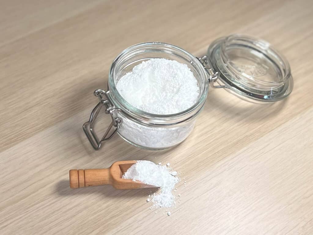 A pot of titanium dioxide sits next to a wooden scoop