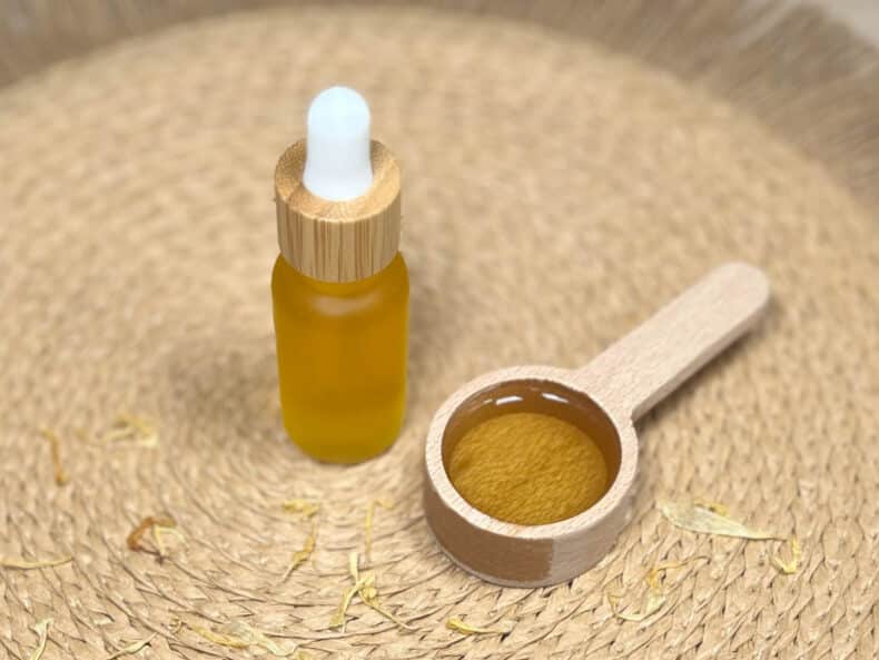 DIY cuticle oil sits next to a spoon with some of the oil in it