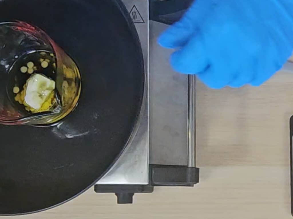 The heatproof container is placed in a water bath so the solid ingredients can melt