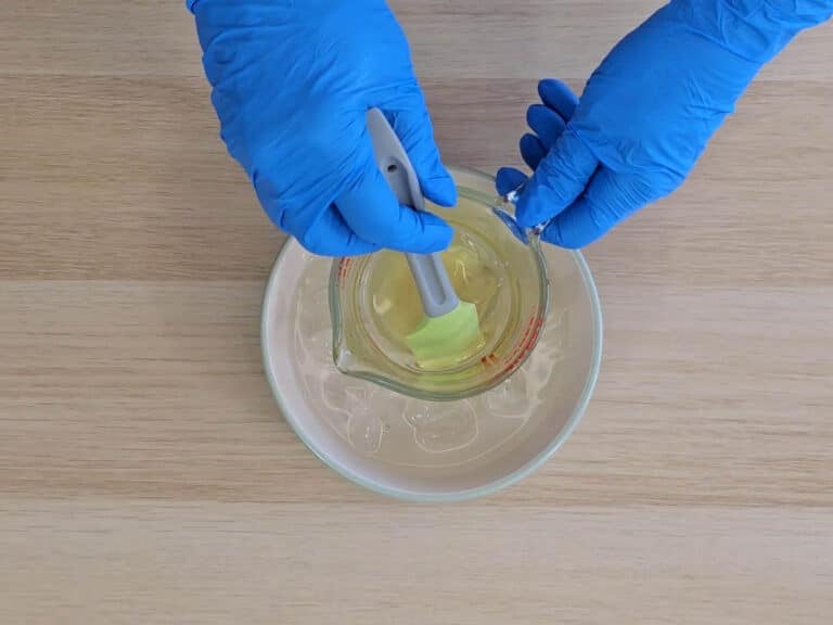 The beaker is lowered into an ice bath to cool as it is stirred