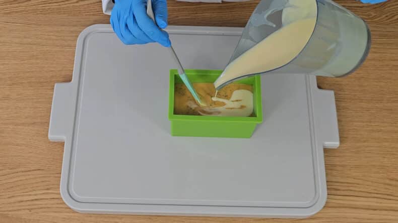 pour around ¾ of the white layer onto the first layer, mixing it in with the stirrer to create an uneven look when it's cut.