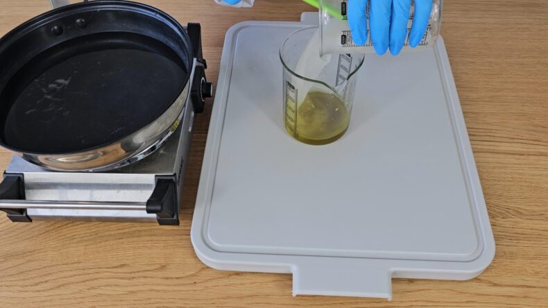 combine by pouring the beaker holding the water into the beaker holding the melted oils