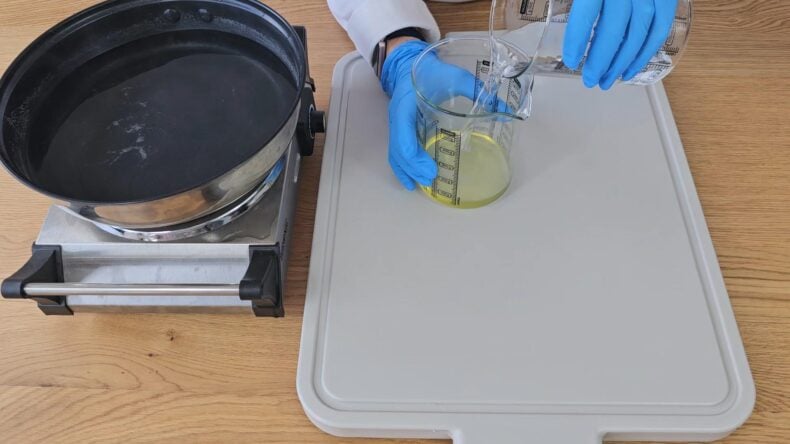 combine by pouring the beaker holding the water into the beaker holding the melted oils