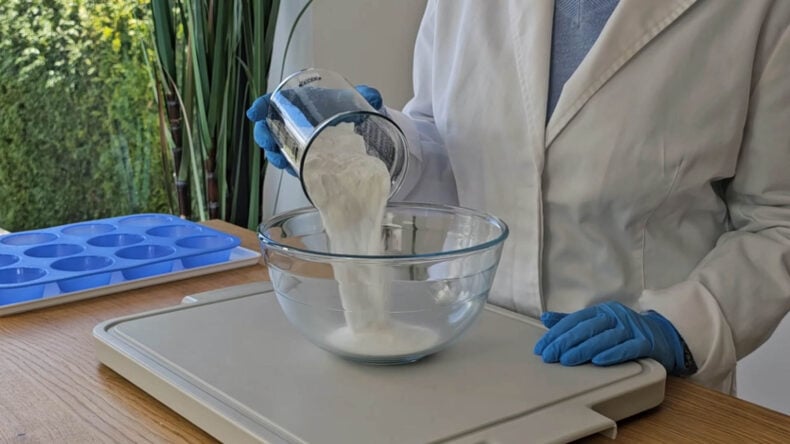 Pouring baking soda into a glass bowl to make DIY shower steamers